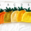 5 crochet pineapple baby hats in different colors of orange, green, yellow, and white